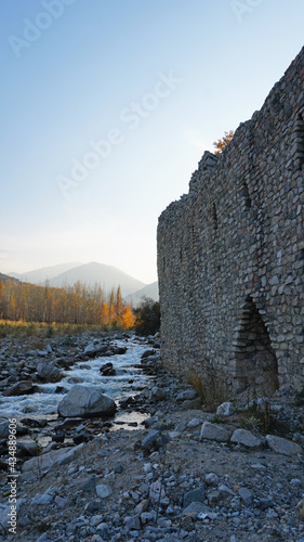 Stone castle, near the walls and inside. Huge stone walls of the fortress. Layer of cement and sand. There are tools for construction. View of the forest, mountains from the fortress. Small window.