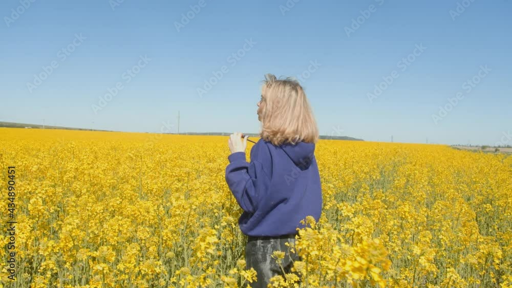 Young woman happy walking through a field and touching yellow flowers. Beautiful carefree woman enjoying nature in blooming field Young woman happy walking through a field and touching yellow flowers. Beautiful carefree woman enjoying nature in blooming field
