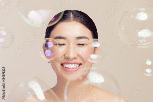 Fashion Asian happy young woman on background soap bubbles, fake eyelashes and makeup