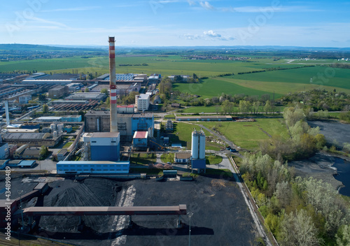 Aerial view of industrial power plant complex against green fields in background. District heating network. Coal heating plant in the end of life cycle.