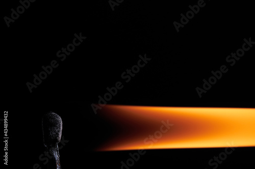 Burning match and extended flame on a black background