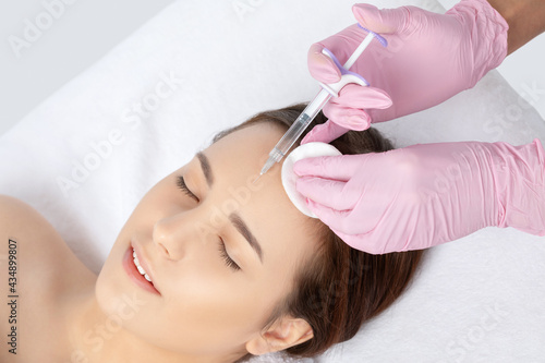 Cosmetologist makes rejuvenating anti wrinkle injections on the face of a beautiful woman. Female aesthetic cosmetology in a beauty salon.