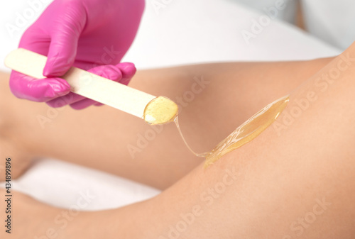 A beautician makes a sugar paste depilation of a woman's legs in a beauty salon. Female aesthetic cosmetology.