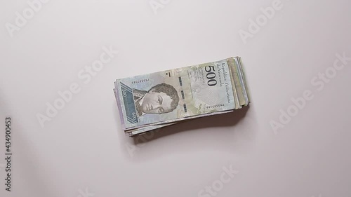 person drops five hundred bolivares on the table and another person picks it up and takes it, bribery, corruption photo