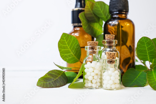 Slika na platnu Homeopathic globules in small glass bottles on a white background