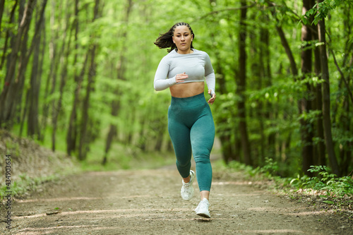 Plus size runner woman in the forest