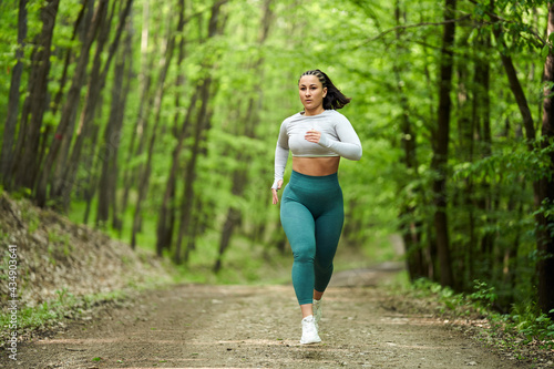 Fototapeta Naklejka Na Ścianę i Meble -  Plus size runner woman in the forest