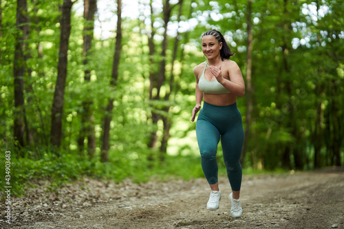Plus size runner woman in the forest