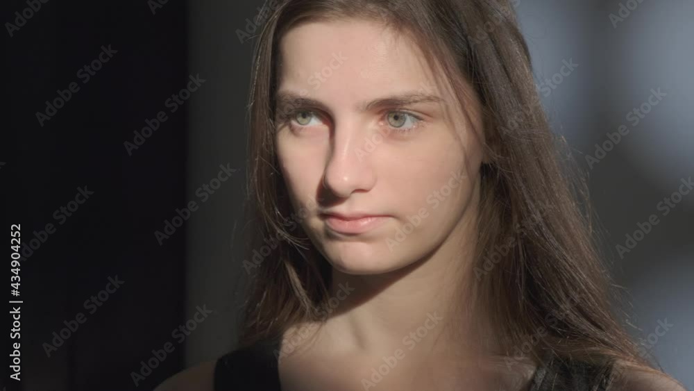 Close up portrait of young girl with brown hair watching calmly into camera in studio.