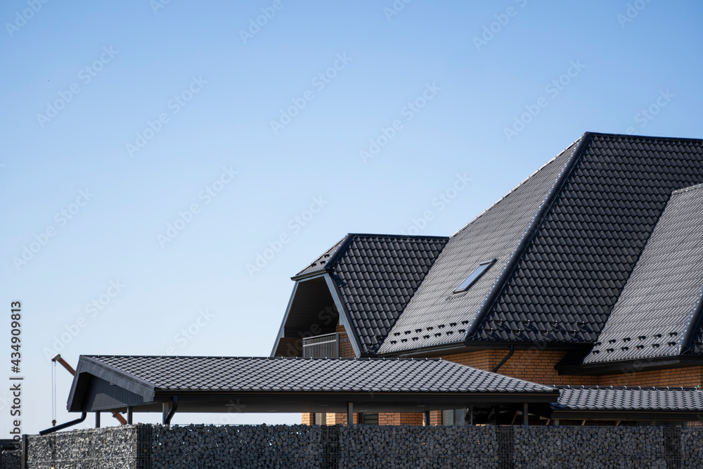 Brown corrugated metal profile roof installed on a modern house. The roof of corrugated sheet. Roofing of metal profile wavy shape. Modern roof made of metal. Metal roofing. Brown corrugated metal profile roof installed on a modern house. The roof of corrugated sheet. Roofing of metal profile wavy shape. Modern roof made of metal. Metal roofing.