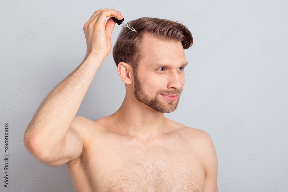 Photo of sweet pretty blond hair young guy no clothes smiling holding arm oil dropper looking empty space isolated grey color background Photo of sweet pretty blond hair young guy no clothes smiling holding arm oil dropper looking empty space isolated grey color background