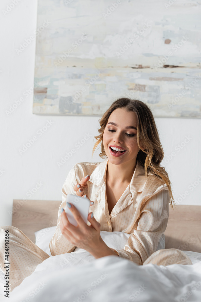 Happy woman pointing at smartphone on bed Happy woman pointing at smartphone on bed