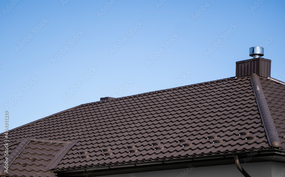 Brown corrugated metal profile roof installed on a modern house. The roof of corrugated sheet. Roofing of metal profile wavy shape. Modern roof made of metal. Metal roofing. Brown corrugated metal profile roof installed on a modern house. The roof of corrugated sheet. Roofing of metal profile wavy shape. Modern roof made of metal. Metal roofing.