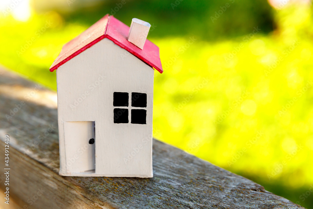 Miniature white toy model house in wooden background near green backdrop. Eco Village, abstract environmental background. Real estate mortgage property insurance dream home ecology concept. Miniature white toy model house in wooden background near green backdrop. Eco Village, abstract environmental background. Real estate mortgage property insurance dream home ecology concept.