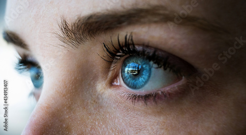 primer plano de los preciosos ojos azules de una chica peliroja con pecas reflejando ventanal en un dia de primavera