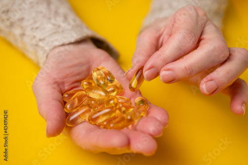 Elderly woman holds fish oil capsules in her hands. Omega 3 and old age.