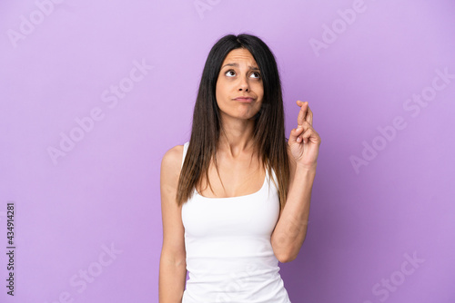 Young caucasian woman isolated on purple background with fingers crossing and wishing the best