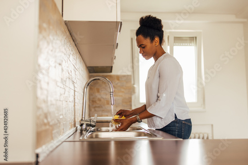 Woman using water and detergent, cleaning dishes.