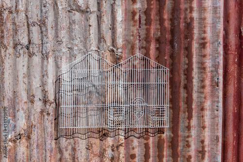 Bird cage against rusty corrugated iron sheets used as decoration