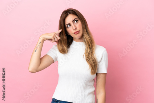 Caucasian woman isolated on pink background making the gesture of madness putting finger on the head