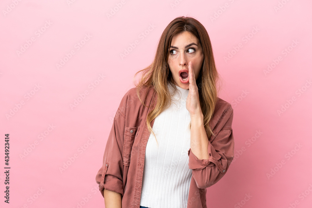 Caucasian woman isolated on pink background whispering something with surprise gesture while looking to the side Caucasian woman isolated on pink background whispering something with surprise gesture while looking to the side