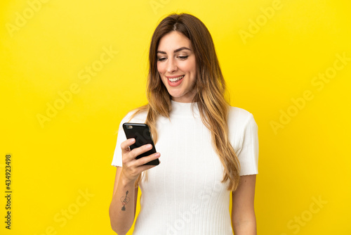 Caucasian woman isolated on yellow background sending a message or email with the mobile