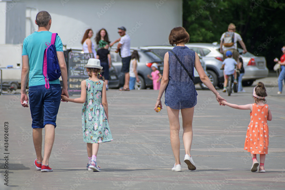 Parents with two girls walk along the city embankment Parents with two girls walk along the city embankment