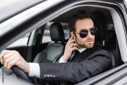 bearded safeguard in sunglasses and suit adjusting security earpiece in car © LIGHTFIELD STUDIOS