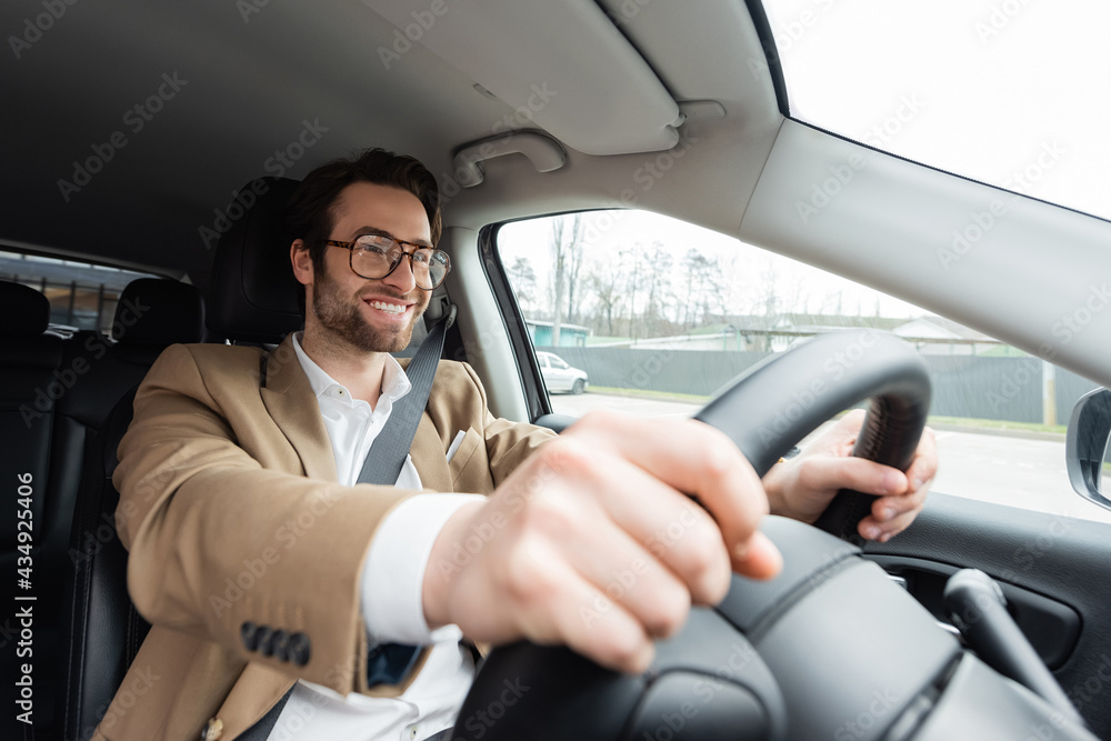 smiling bearded man in glasses driving modern car