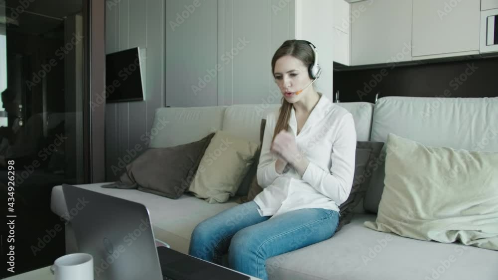Young Business Woman Wearing Headphones Communicating By Video Call. Speaking Looking At Laptop Computer, Online Conference Distance Office Chat, Virtual Training Concept Young Business Woman Wearing Headphones Communicating By Video Call. Speaking Looking At Laptop Computer, Online Conference Distance Office Chat, Virtual Training Concept