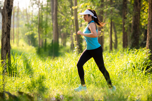 Healthy woman jogging run and workout in forest outdoor. Asian runner people exercise gym with fitness session, nature park background. Health and Lifestyle Concept.