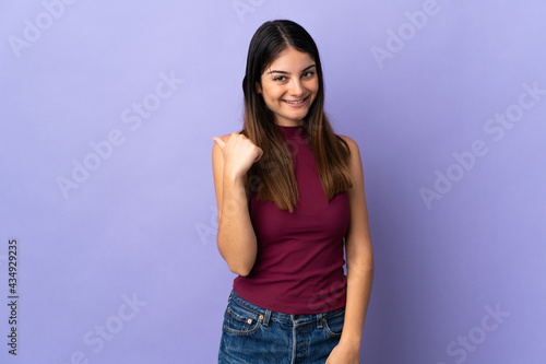 Young caucasian woman isolated on purple background pointing to the side to present a product
