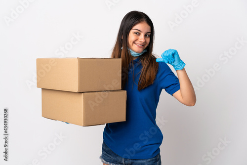 Young delivery woman protecting from the coronavirus with a mask isolated on white background proud and self-satisfied