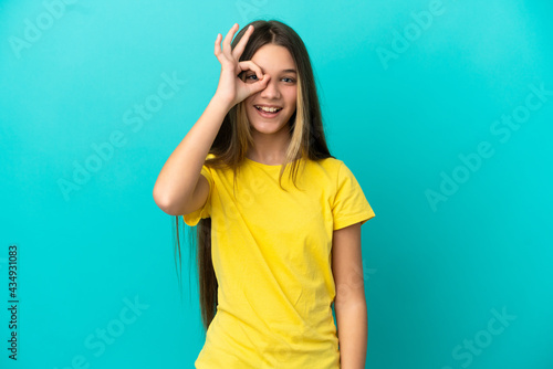 Little girl over isolated blue background showing ok sign with fingers