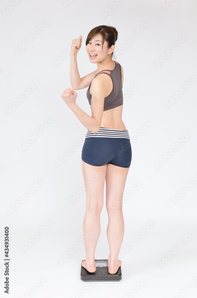 ヘルスメーターに乗って喜ぶ若い女性 ヘルスメーターに乗って喜ぶ若い女性
