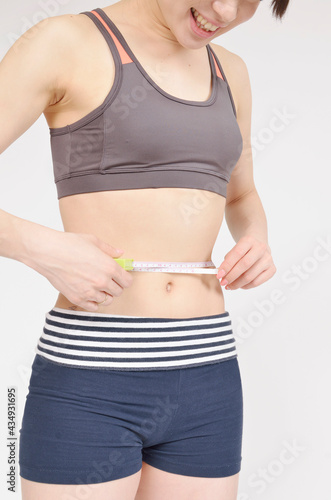 メジャーで腹囲を測る若い女性
