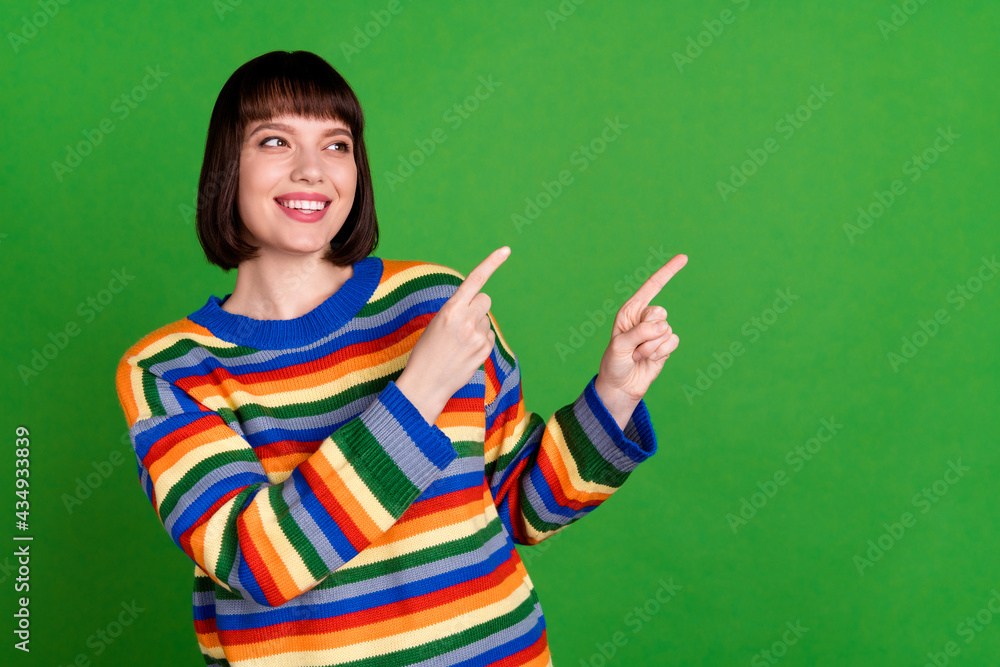 Photo of attractive happy positive young woman look point fingers empty space information isolated on green color background Photo of attractive happy positive young woman look point fingers empty space information isolated on green color background