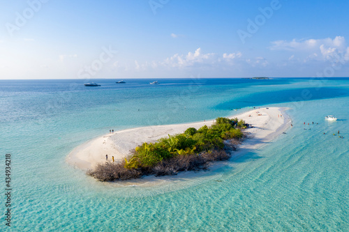 Aerial view of travelers on a small sandy island and touris tships on the horizon in the Indian Ocean