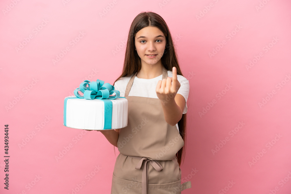 Little girl with a big cake over isolated pink background doing coming gesture Little girl with a big cake over isolated pink background doing coming gesture