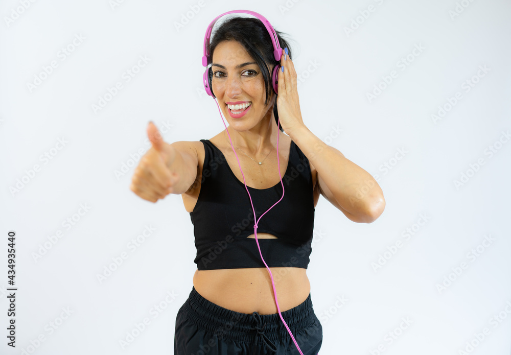 Fitness woman in sportswear and headphones with thumb up isolated over white background. Fitness woman in sportswear and headphones with thumb up isolated over white background.