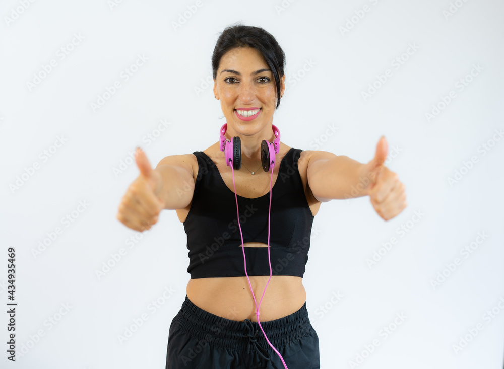 Fitness woman in sportswear and headphones with thumbs up isolated over white background. Fitness woman in sportswear and headphones with thumbs up isolated over white background.