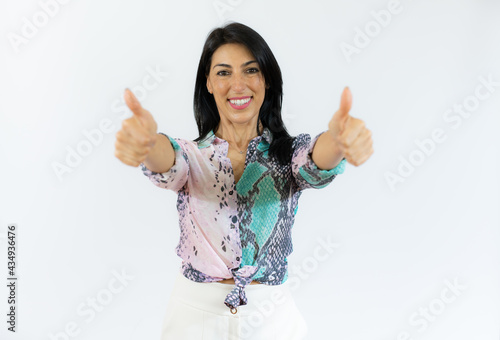 Smiling woman in casual shirt with thumbs up over white background.