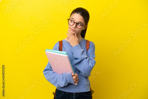 Student kid woman over isolated yellow background looking up while smiling