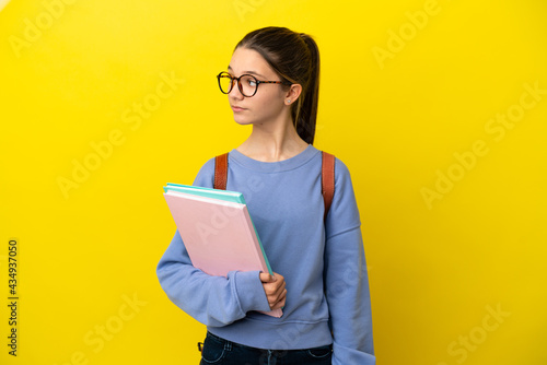 Student kid woman over isolated yellow background looking to the side