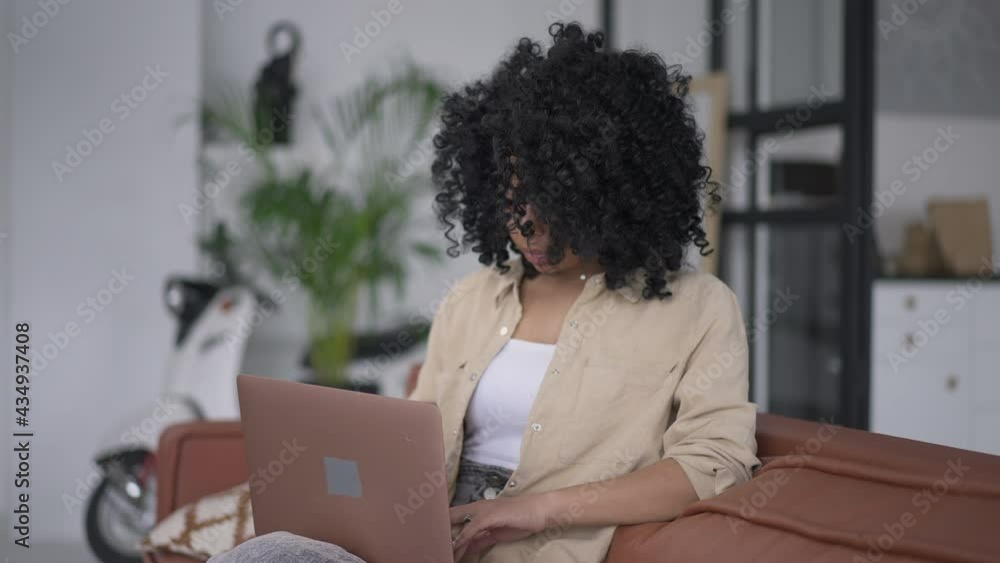 Focused African American young woman typing on laptop keyboard messaging online. Concentrated young beautiful slim manager thinking texting e-mail to business partner from home office Focused African American young woman typing on laptop keyboard messaging online. Concentrated young beautiful slim manager thinking texting e-mail to business partner from home office