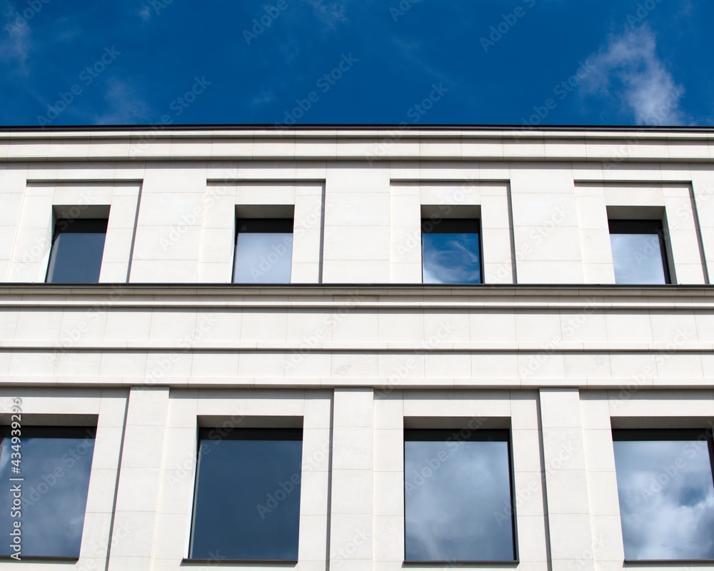 Building facade on blue sky background. Reflection of blue sky in windows of building