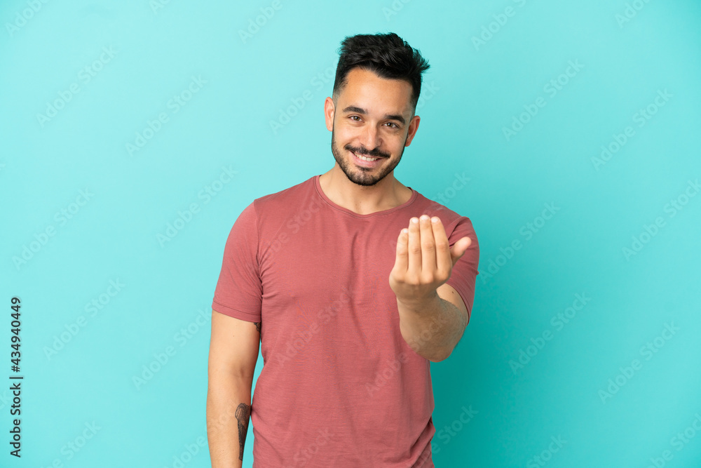 Young caucasian man isolated on blue background inviting to come with hand. Happy that you came Young caucasian man isolated on blue background inviting to come with hand. Happy that you came