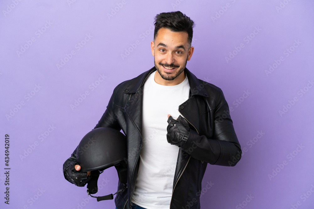 Young man with a motorcycle helmet isolated on purple background with surprise facial expression Young man with a motorcycle helmet isolated on purple background with surprise facial expression