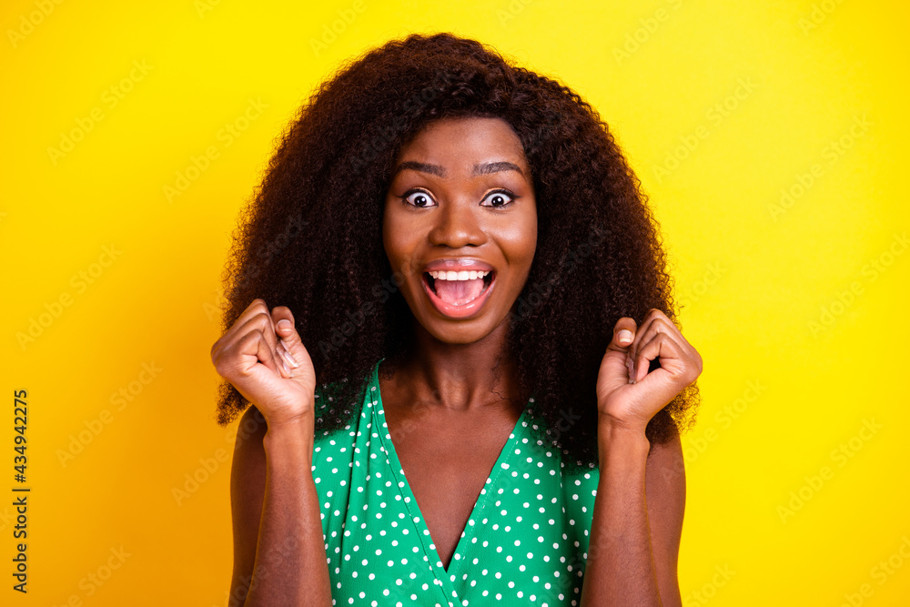 Photo portrait of woman curly hair overjoyed gesturing like winner isolated vibrant yellow color background Photo portrait of woman curly hair overjoyed gesturing like winner isolated vibrant yellow color background