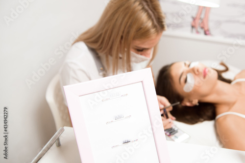 Beautiful young woman during eyelash extension in a salon.